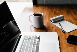 Desk with coffee, notebook, and laptop symbolising article and blog writing